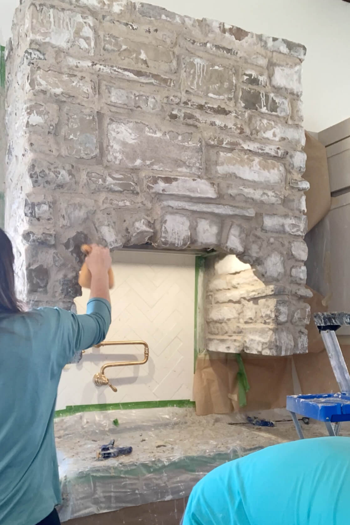 Cleaning off DIY stone range hood with a sponge. 
